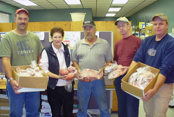 Photo de quelques membres de la Section remettant la viande toute prête et emballée à une banque alimentaire locale